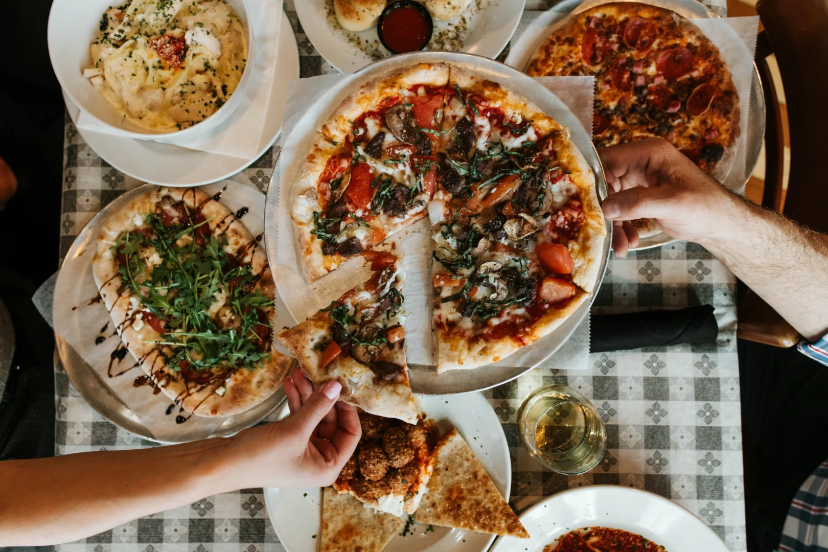 Hand reaching for pizza at Buckhead Pizza Co. in Atlanta, Ga